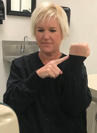 Figure 3: Pull the cuff of the lab coat above the wrist, which represents the CEJ, to show how inflammation can cause the gum line to cover more of the crown of the tooth.