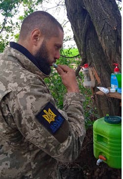 A Ukrainian soldier brushes his teeth at a washing station. A Ukrainian soldier brushes his teeth at a washing station.