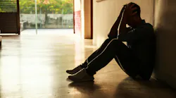 Sad person sitting against wall
