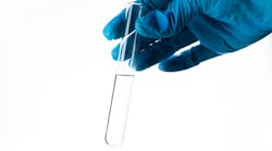 A gloved hand holding a test tube of water A gloved hand holding a test tube of water