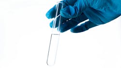 A gloved hand holding a test tube of water A gloved hand holding a test tube of water