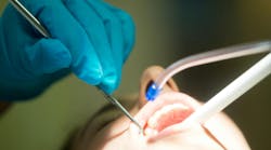 Hygienist using suction device on patient Hygienist using suction device on patient