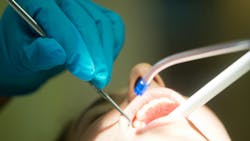 Hygienist using suction device on patient Hygienist using suction device on patient