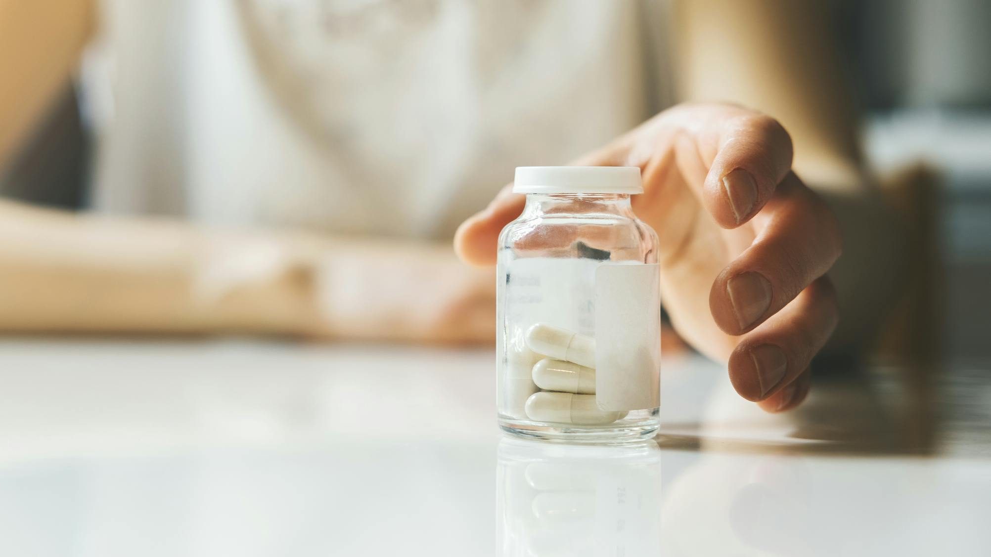 hand_reaching_for_bottle_of_pills