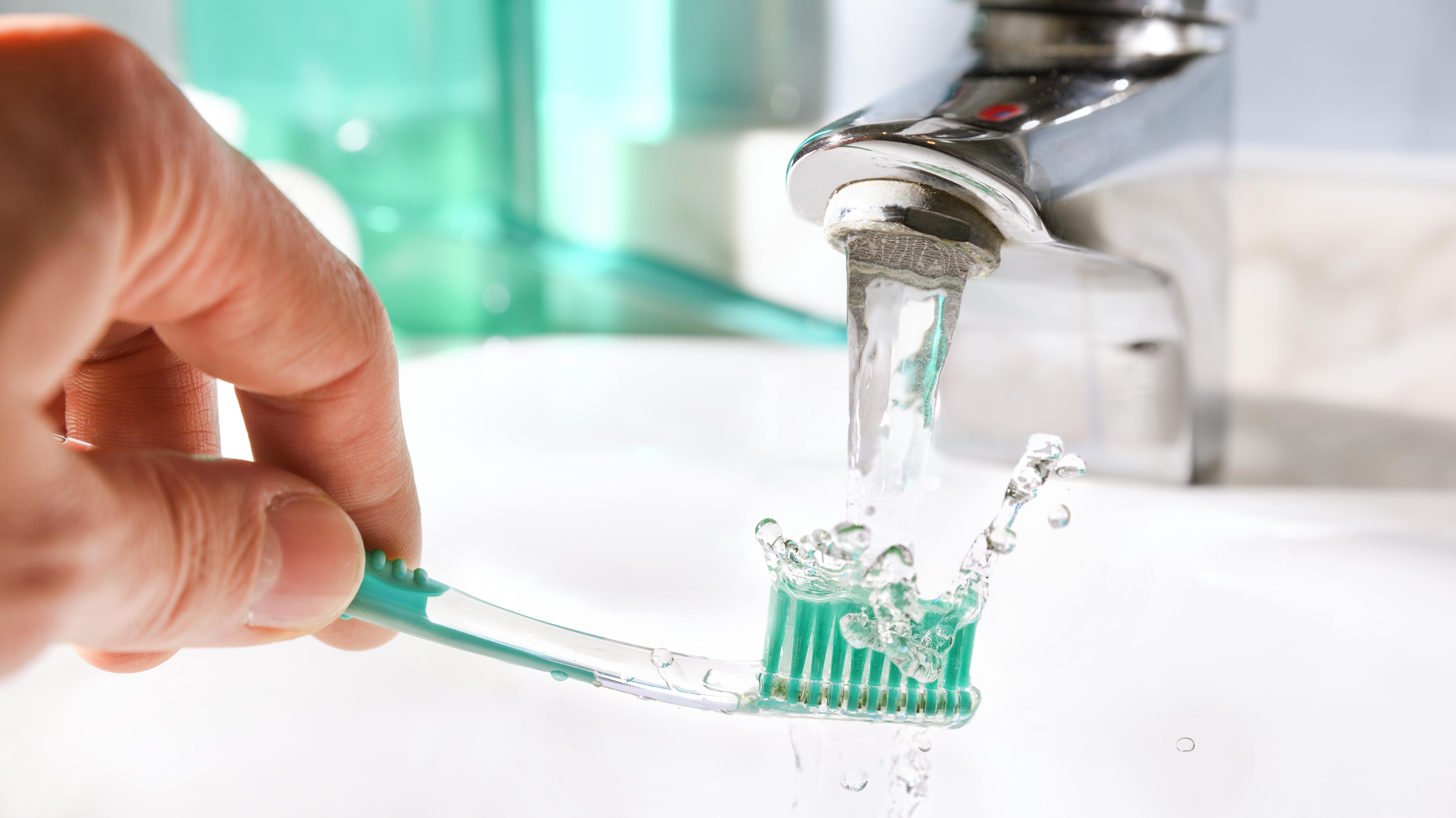 a toothbrush being held under the faucet