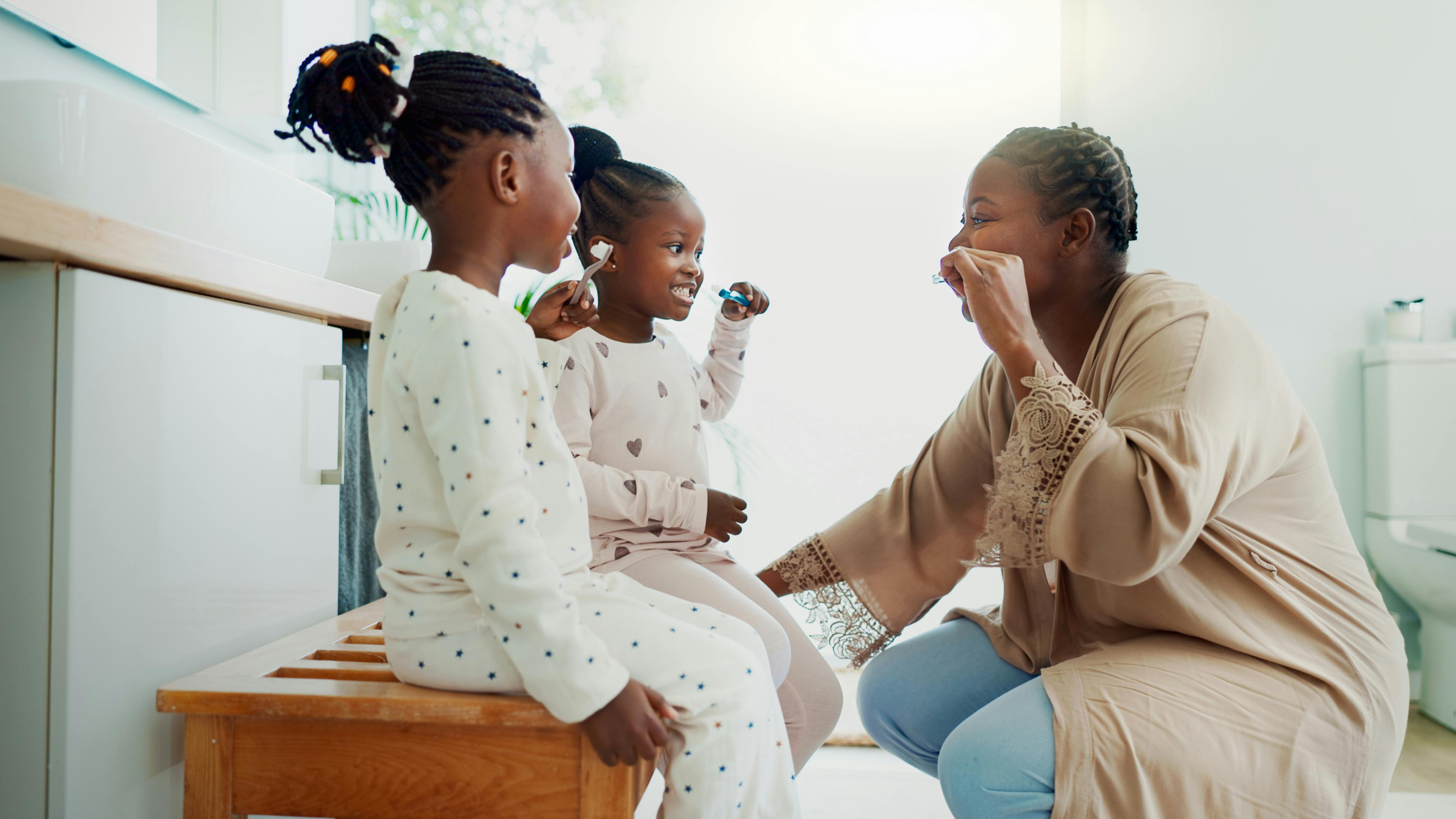 a mom brushing teeth with her two children