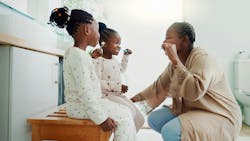 a mom brushing teeth with her two children a mom brushing teeth with her two children