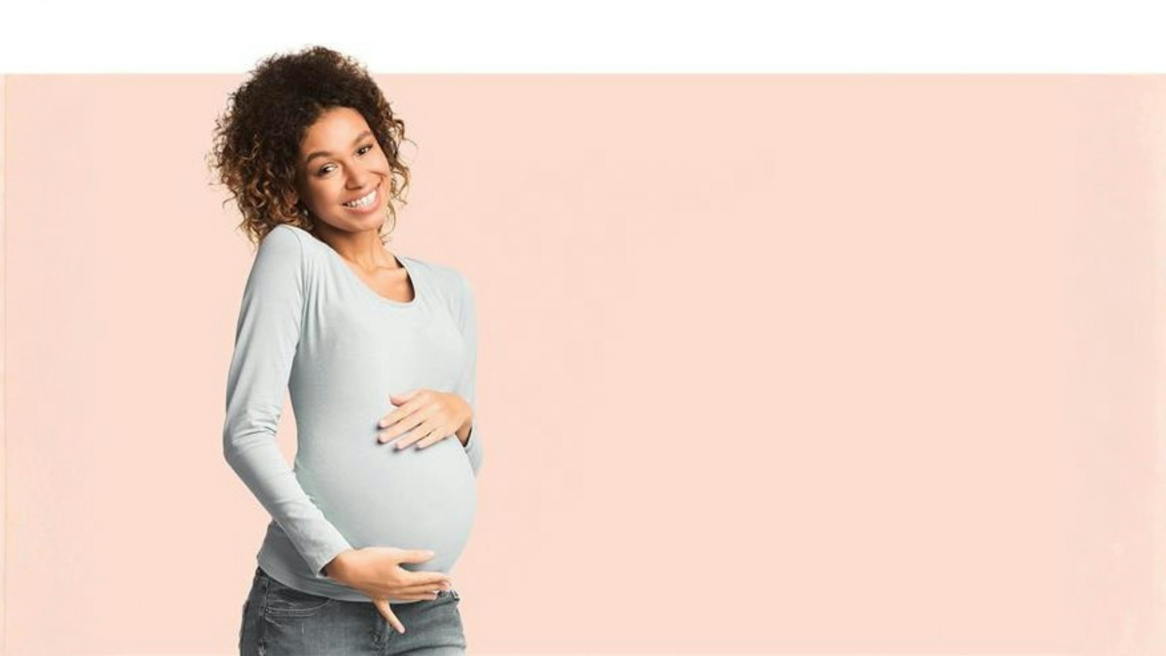 Pregnant woman smiles at camera