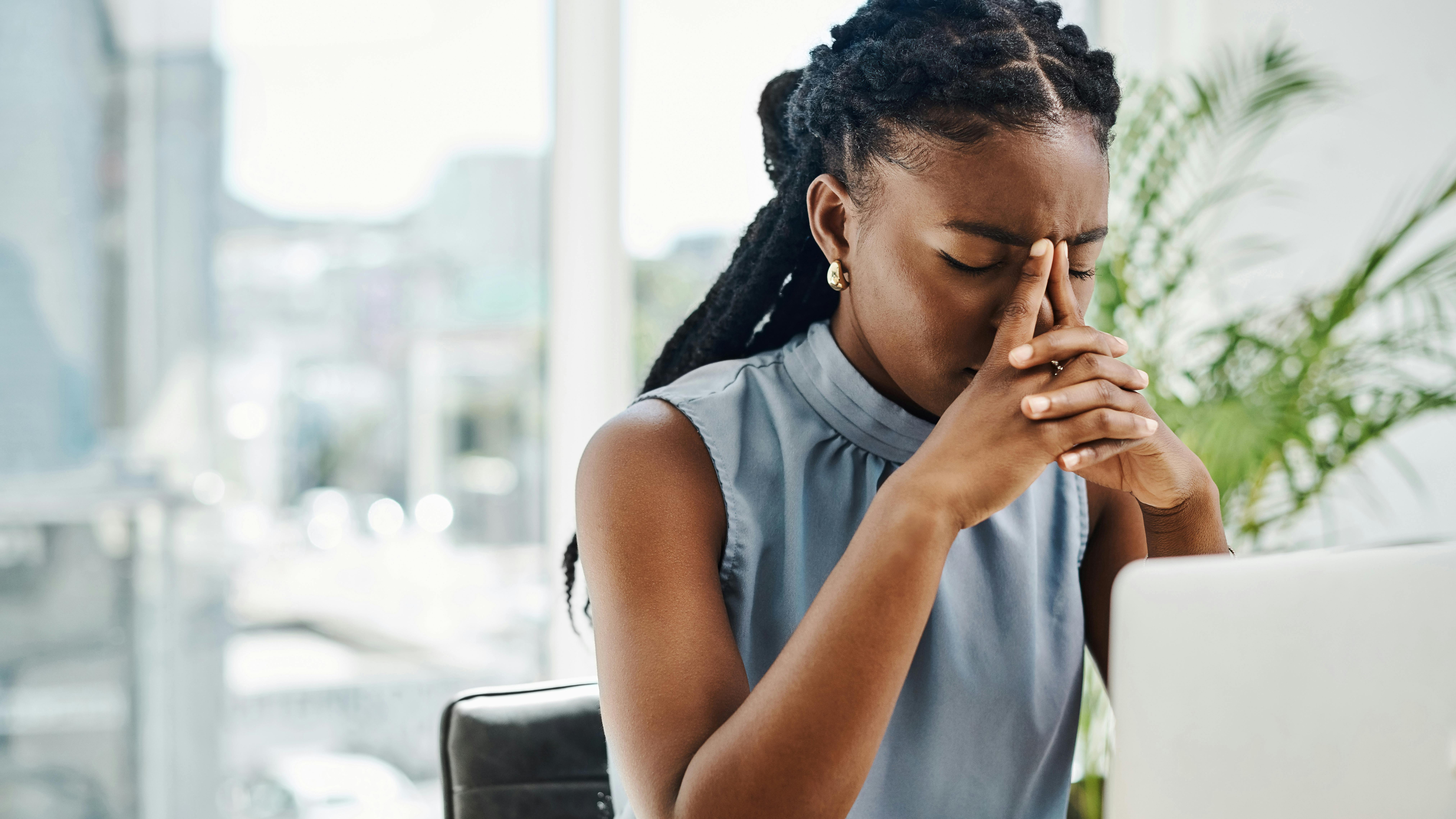 woman sitting at a computer with her hands covering her face illustrating frustration