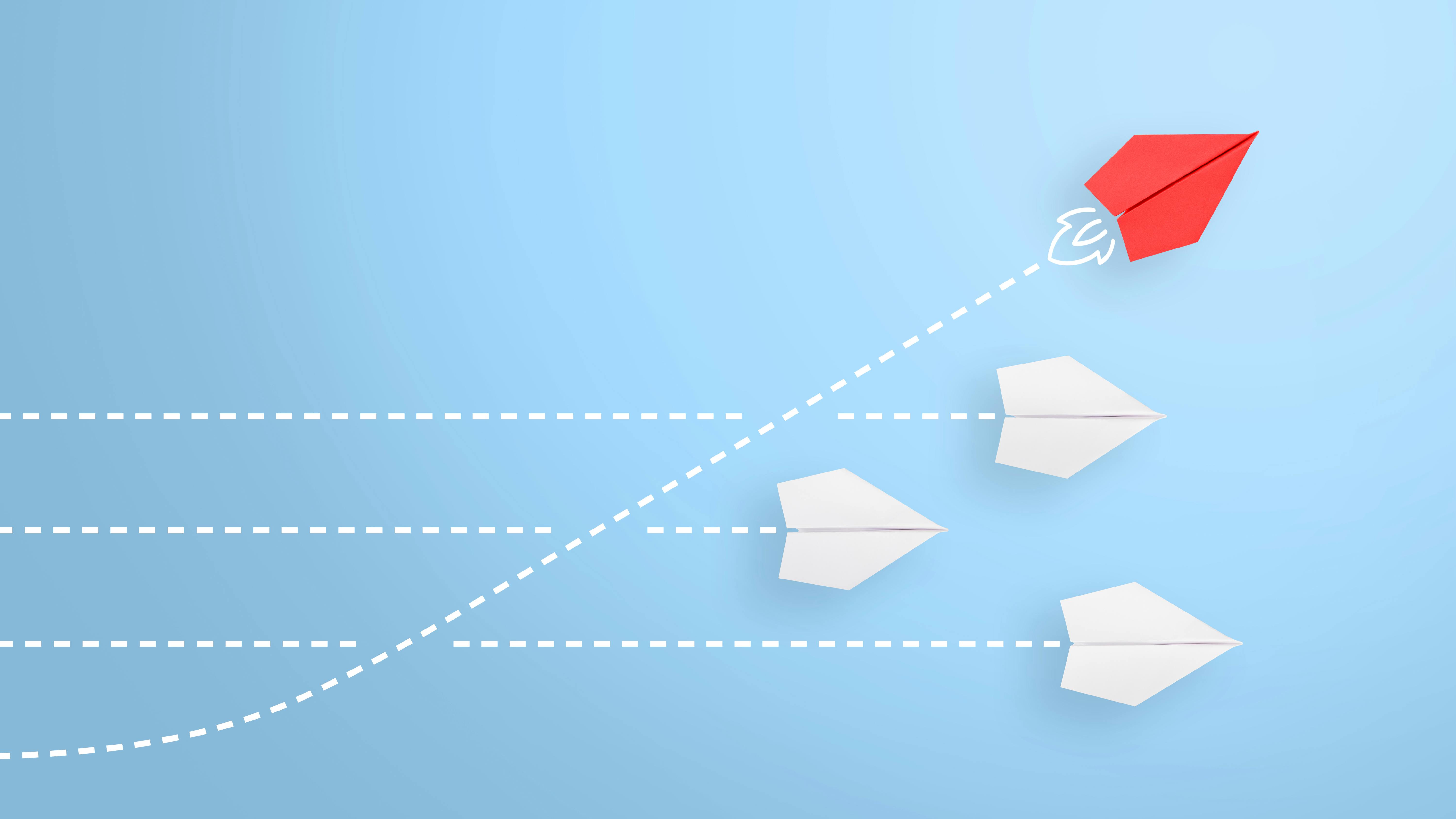3 white paper airplanes on a horizontal trajectory; 1 red paper airplane on an upward trajectory representing leadership