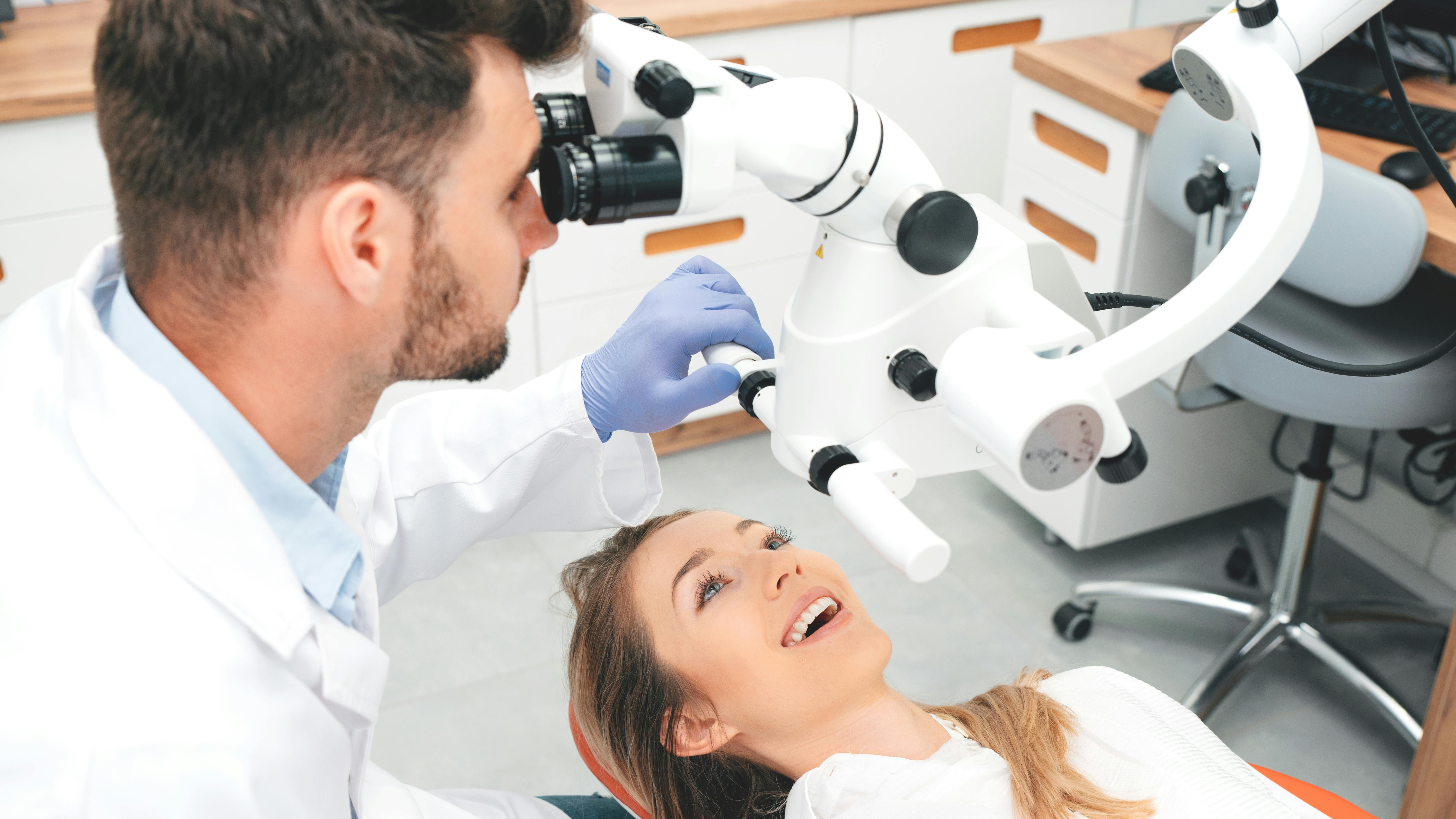 a dental professional using microscope technology on a dental patient