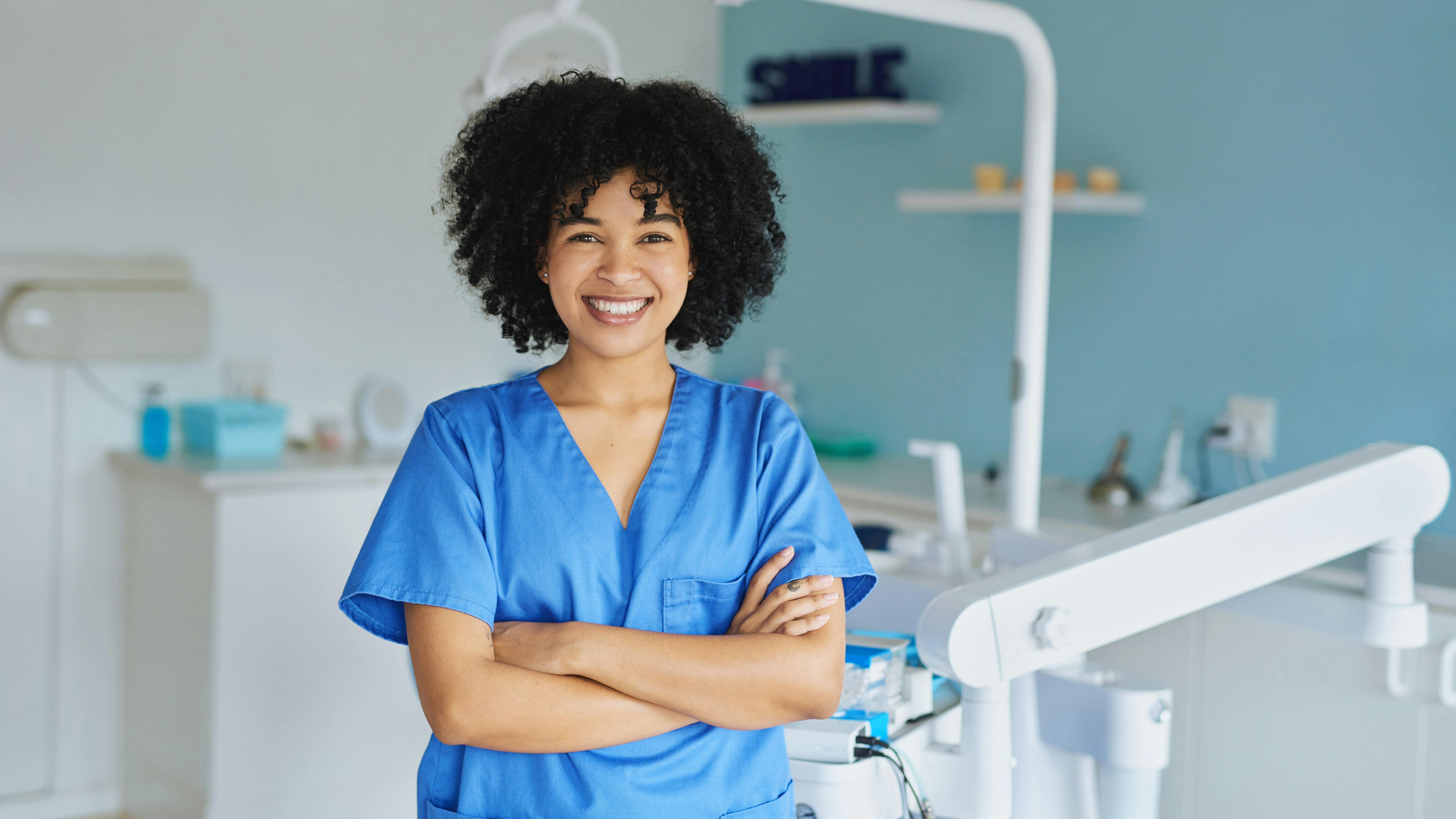 a dental hygienist standing in an operatory smiling