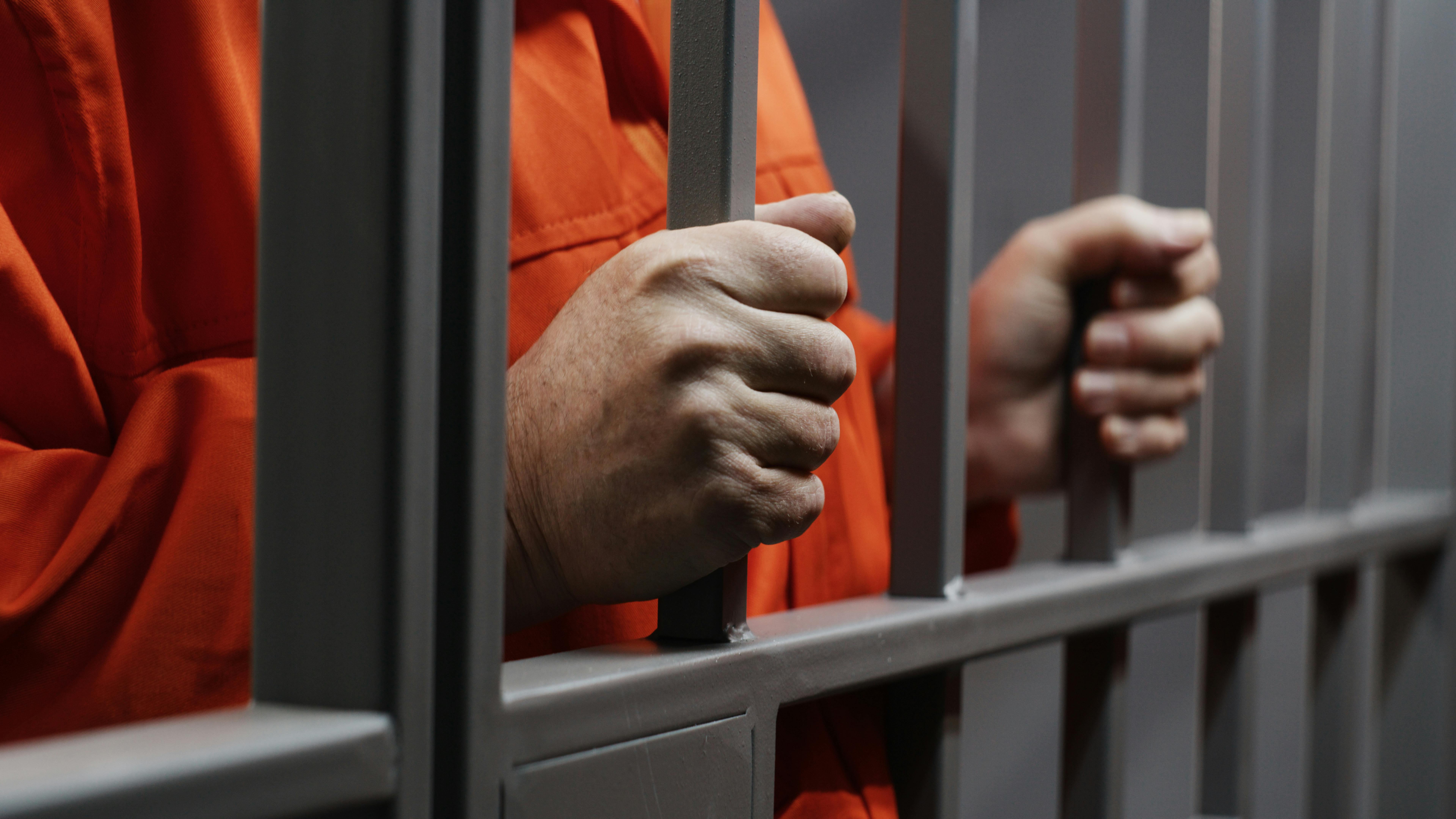 a prison inmate standing behind bars