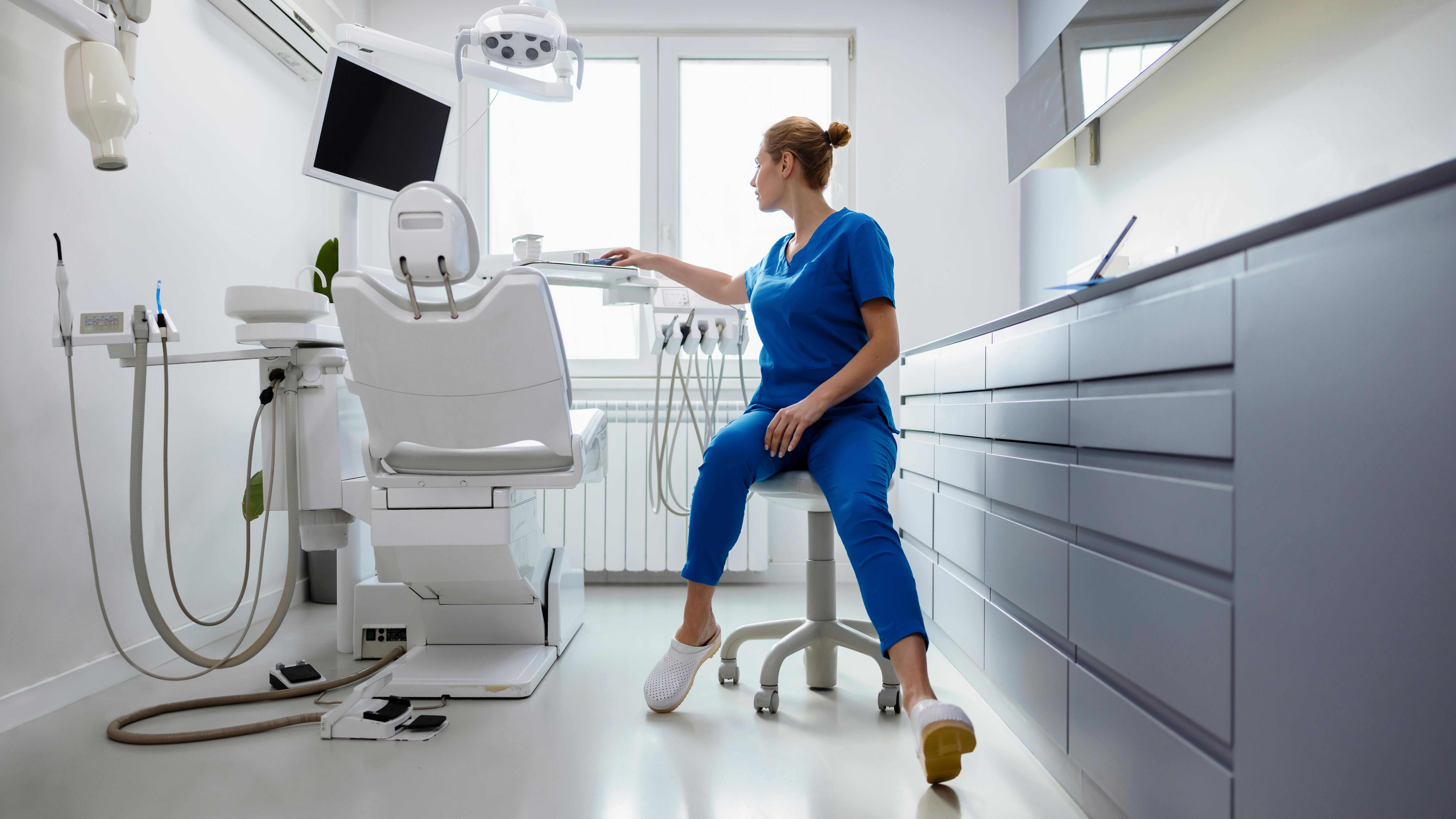 thoughtful dental hygienist standing in empty operatory