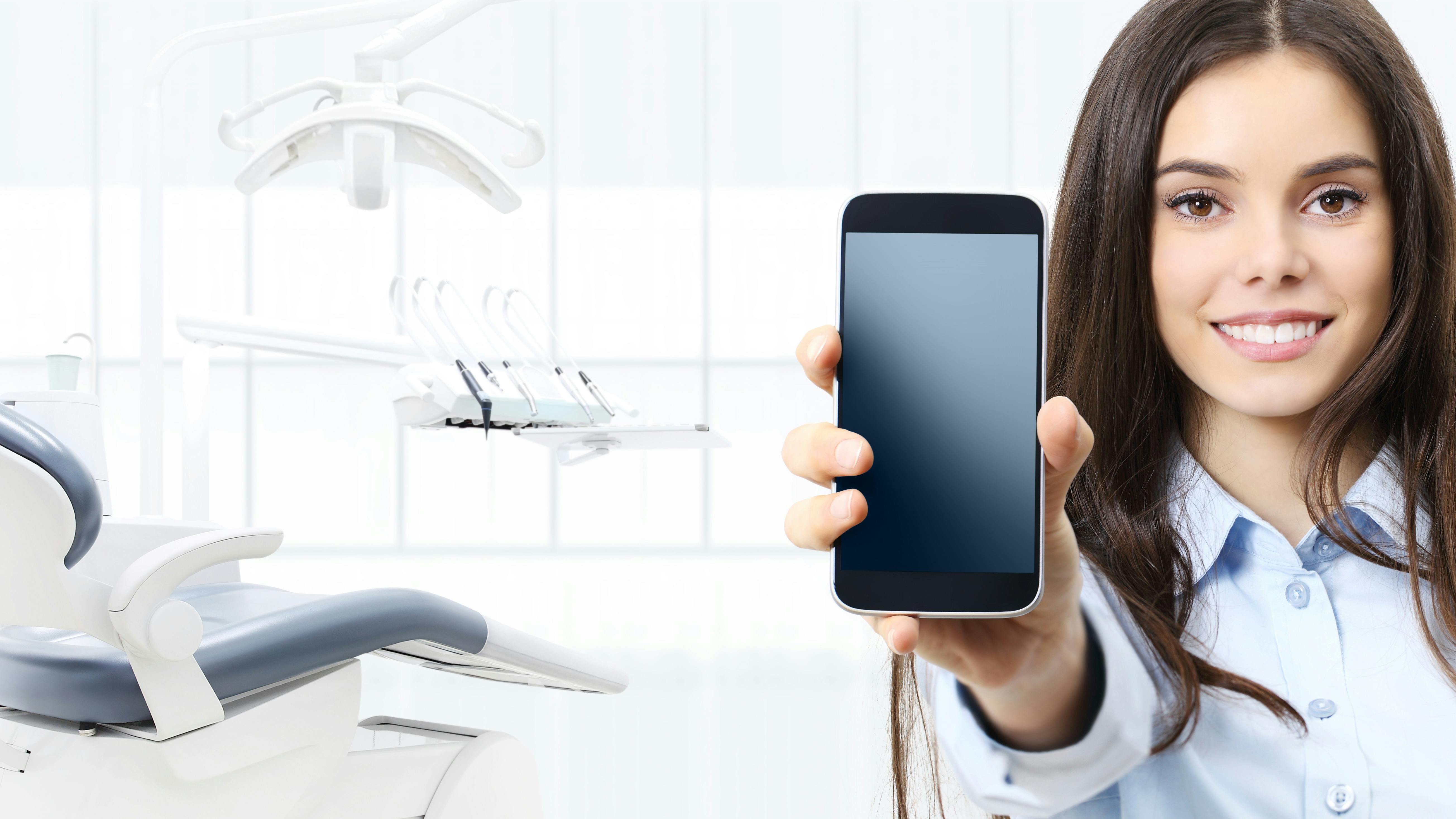 hygienist in an operatory holding a mobile phone