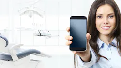 hygienist in an operatory holding a mobile phone