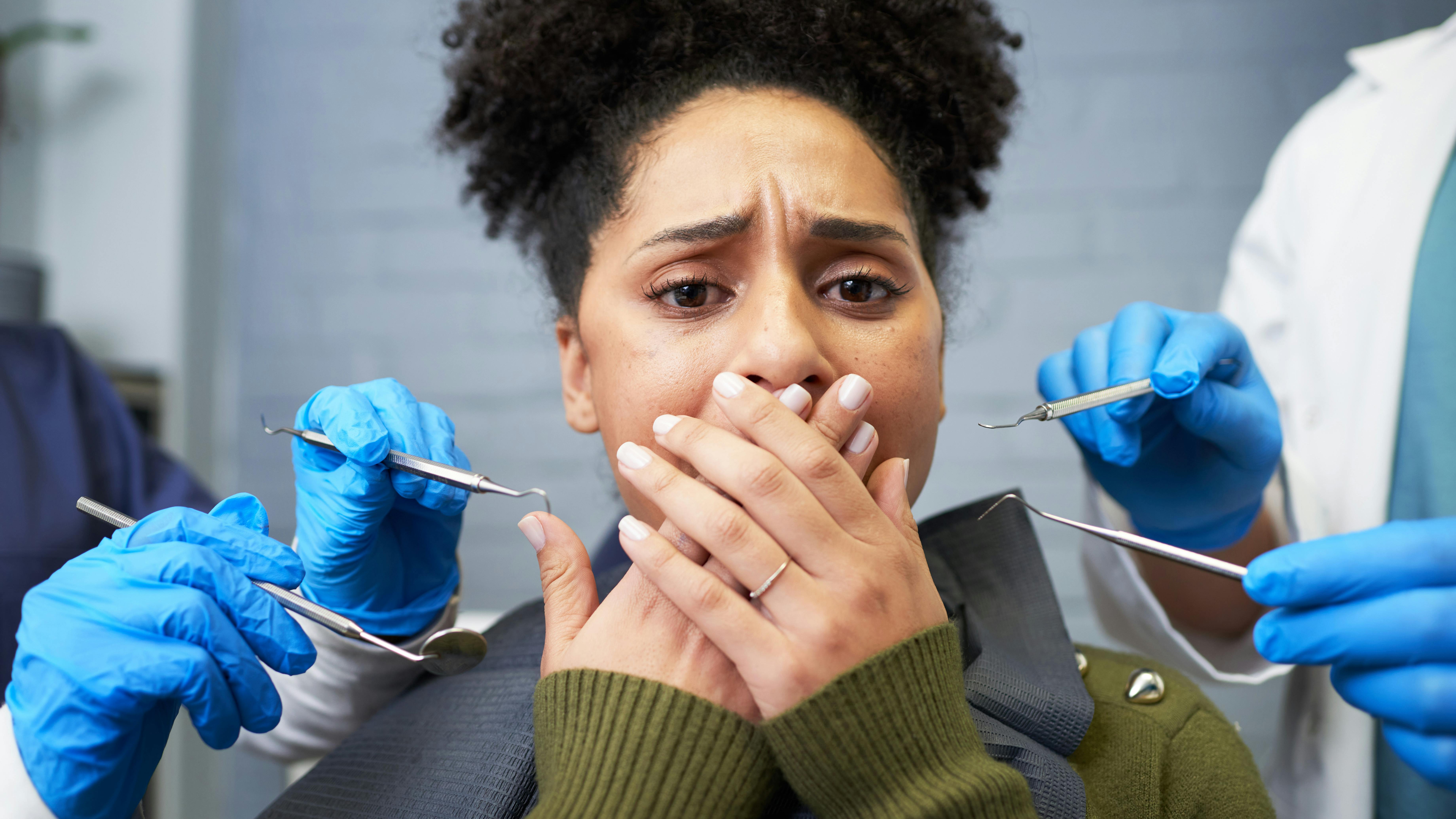 anxious dental patient with her hands over her mouth