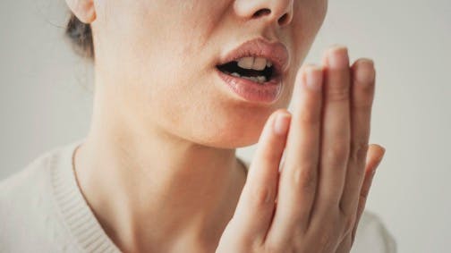 woman exhaling on her hand to test her breath