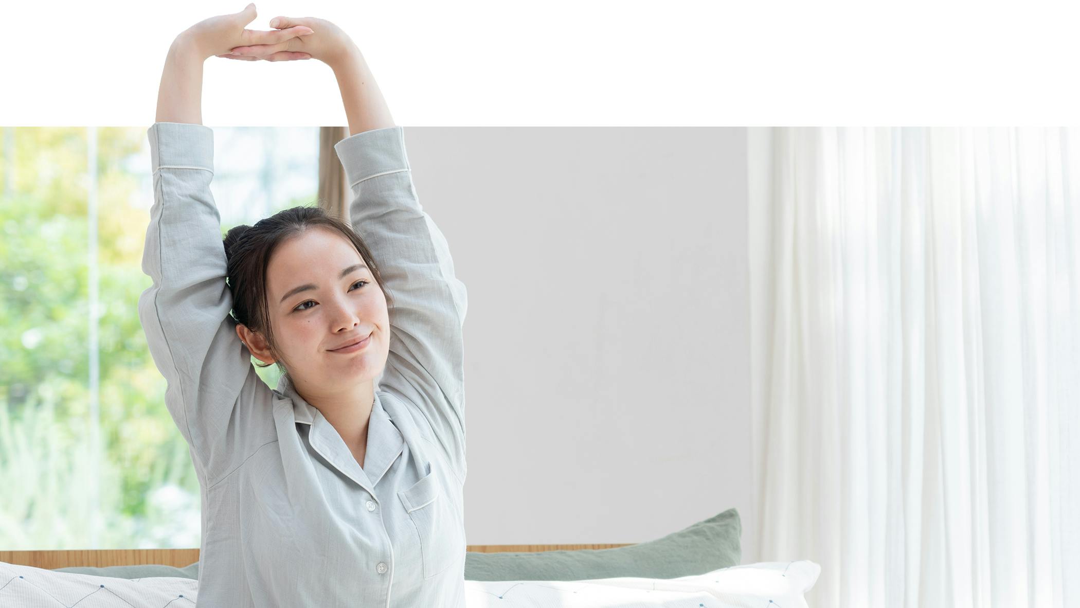 Woman sitting up in bed, stretching arms skyward
