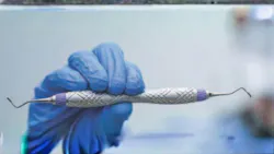 Gloved hand holding curette