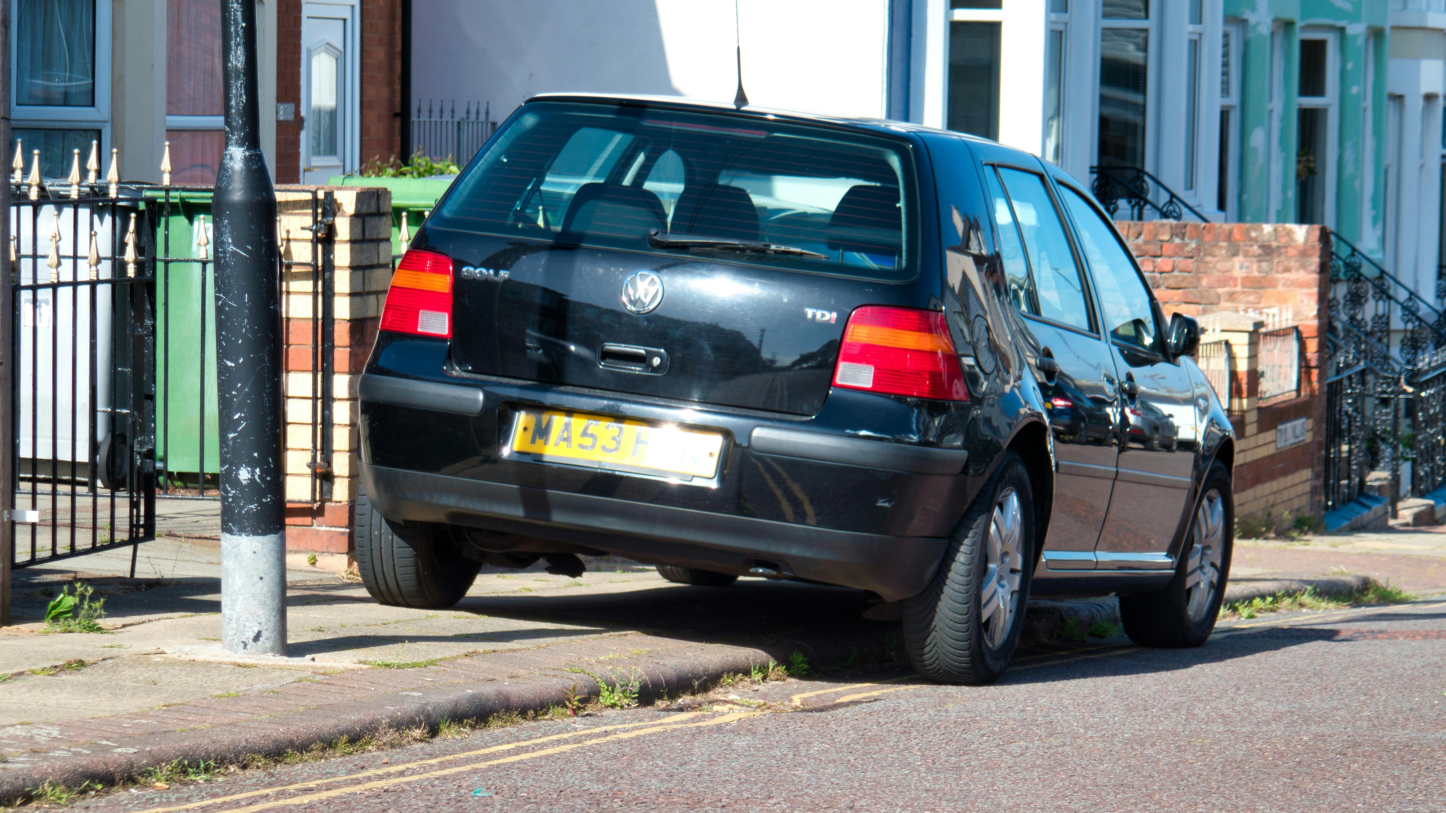 a small car parked halfway on the sidewalk