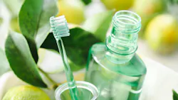 a toothbrush and mouthwash against a backdrop of leaves