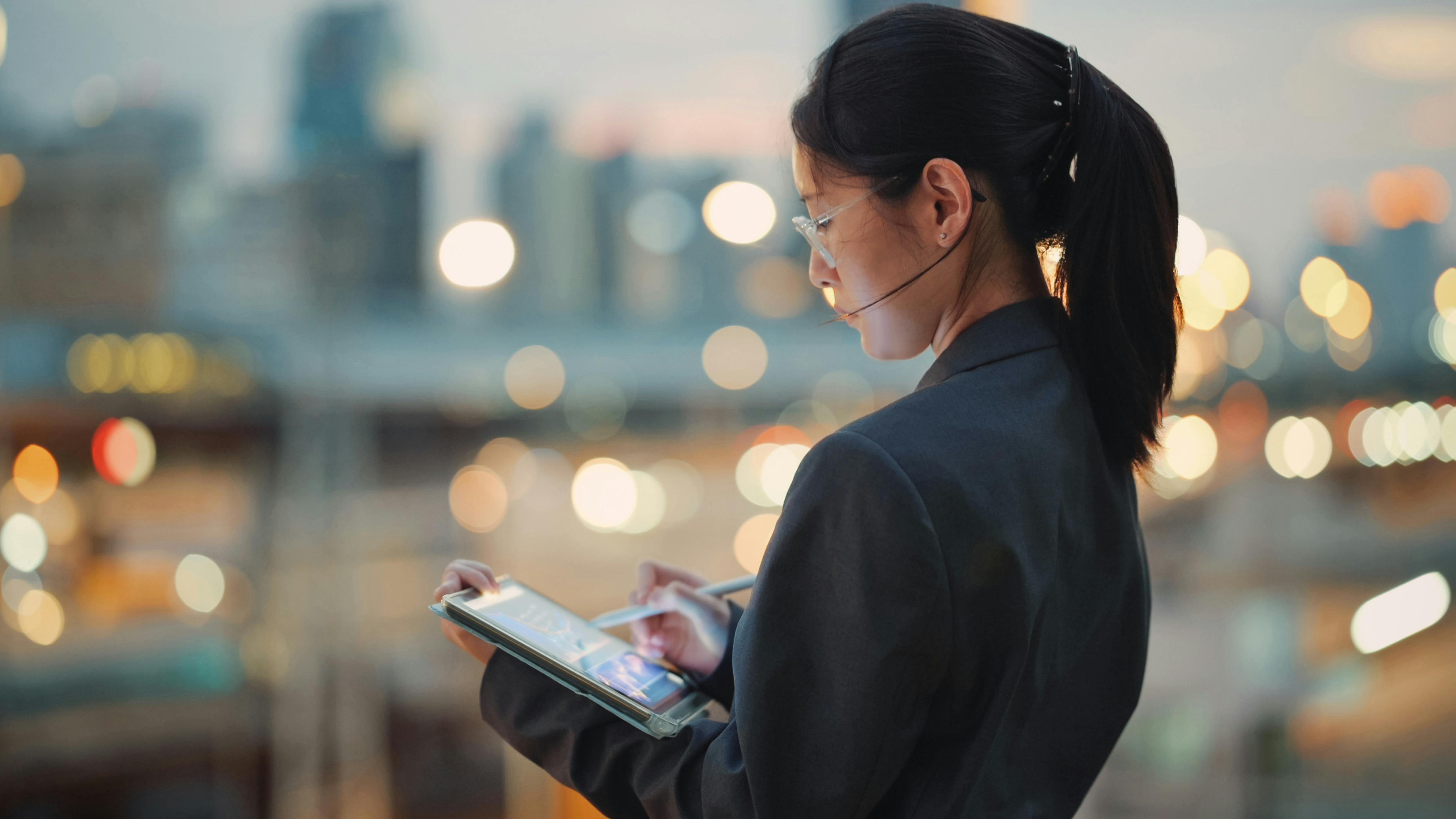 woman looking down at a tablet with bokeh in the background