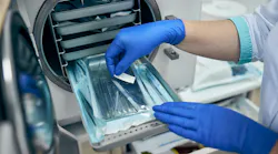 a dental professional's gloved hands working with the instruments in the sterilizer