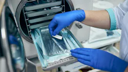 a dental professional's gloved hands working with the instruments in the sterilizer