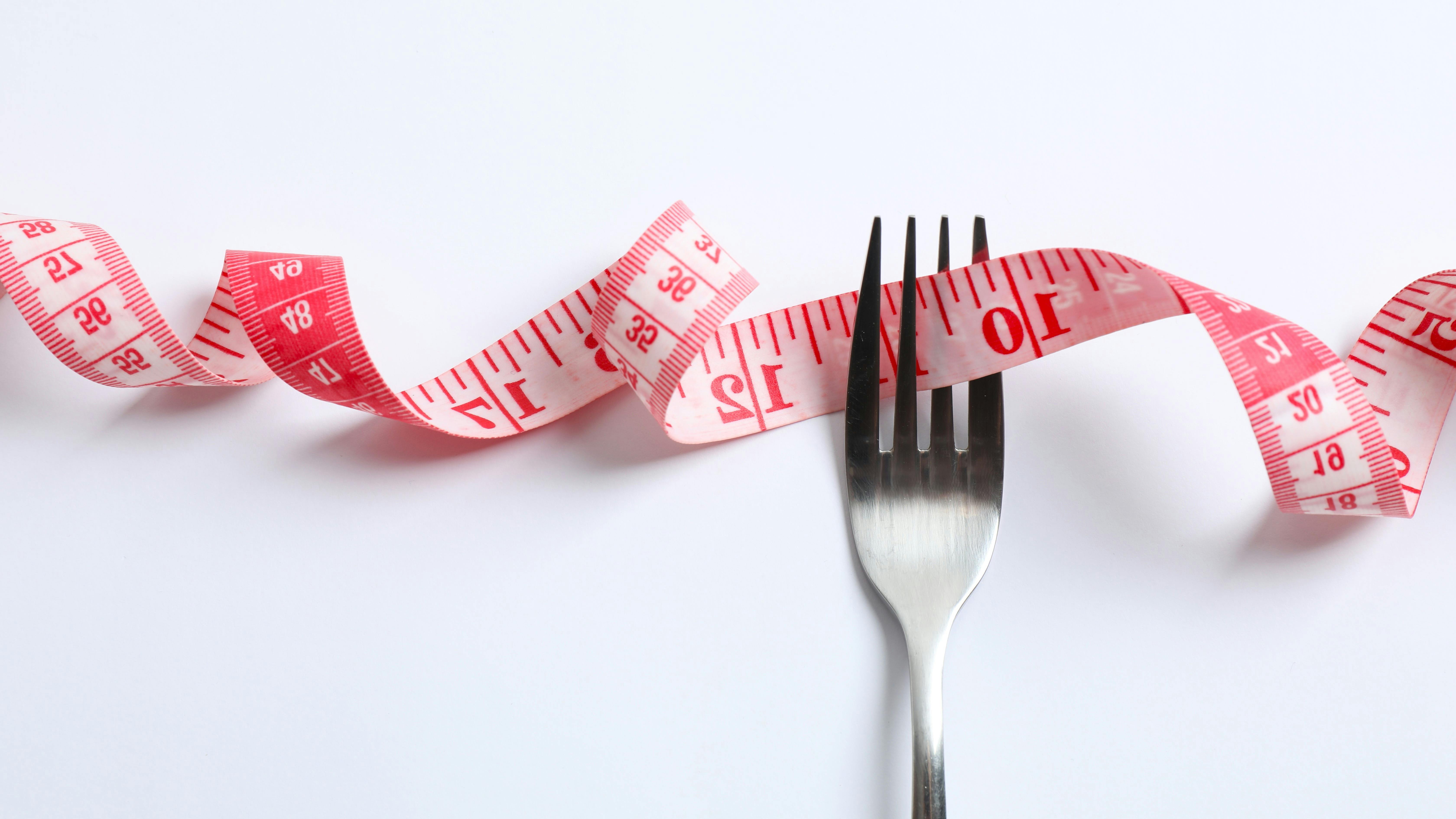 a fork with a measuring tape running through its tines